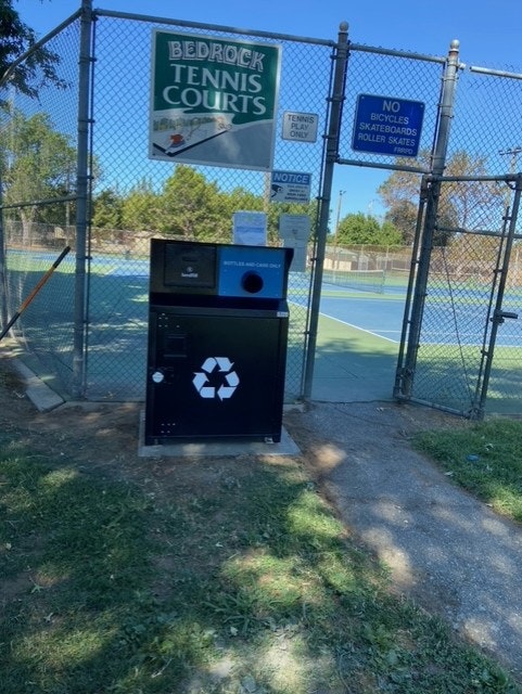 A recycling bin outside Bedrock Tennis Courts with signs prohibiting bicycles, skateboards, and roller skates.