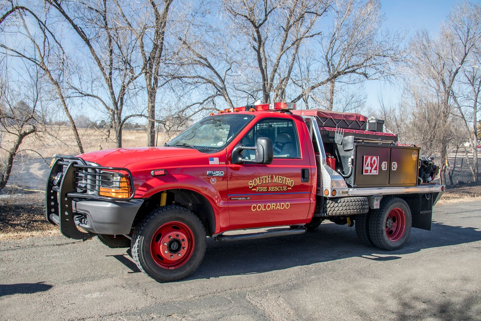 A red fire rescue truck marked "South Metro Fire Rescue, Colorado," parked near trees, ready for emergency response.
