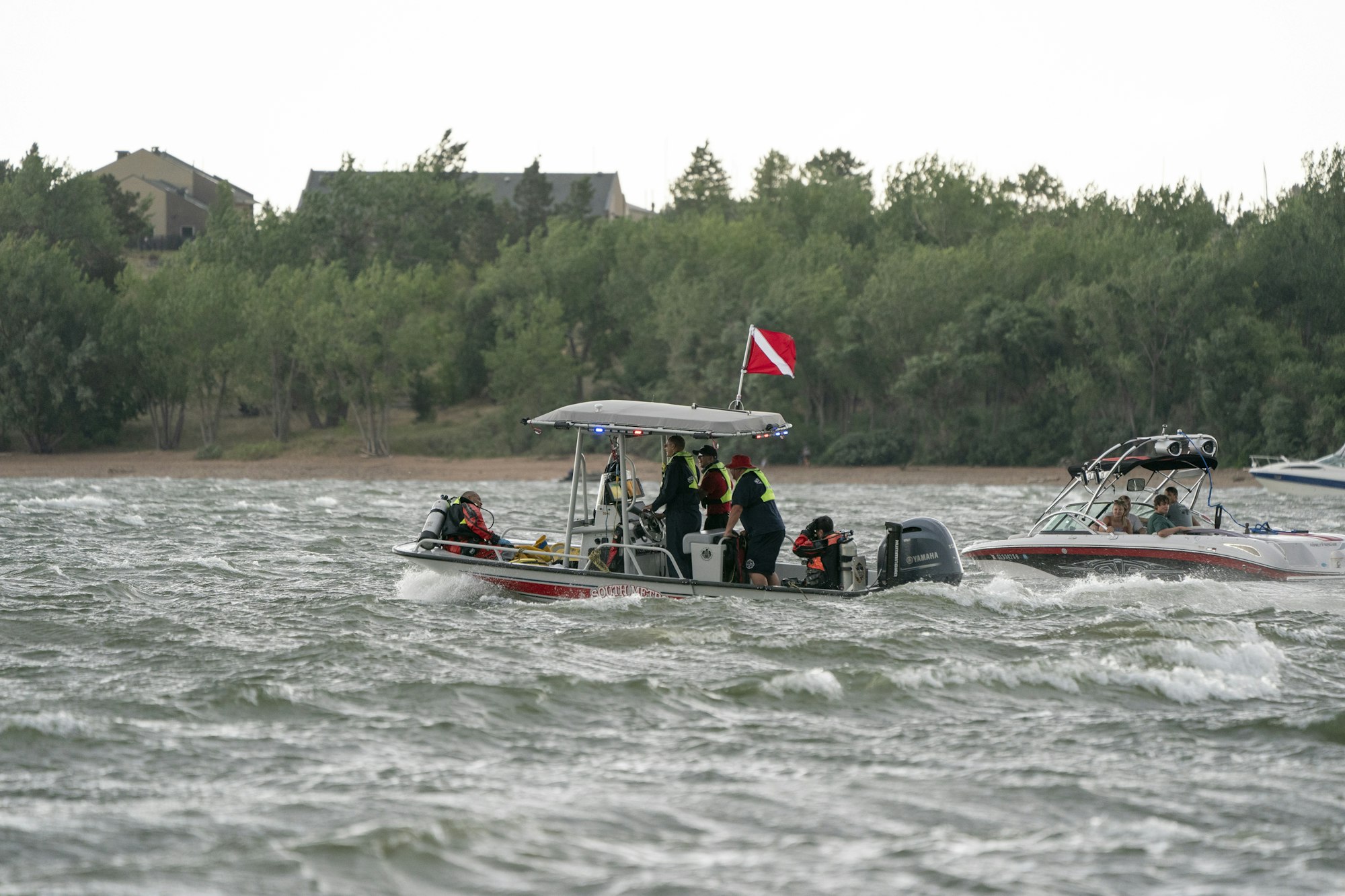 A rescue boat with divers and safety equipment navigates rough waters, while another boat is nearby.