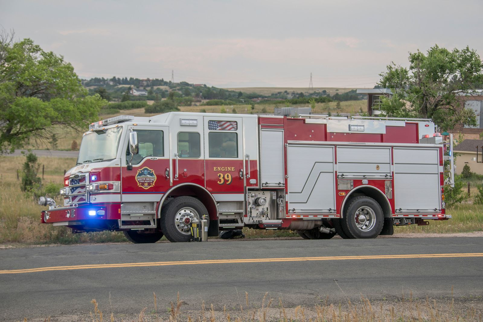 A red and white fire truck labeled "Engine 39" parked near a road in a grassy area.