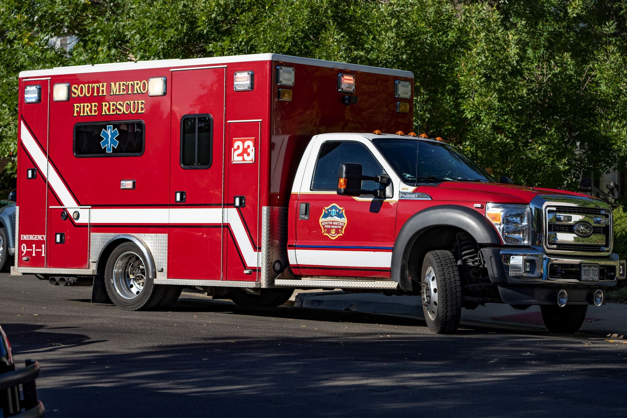 A red South Metro Fire Rescue ambulance parked on the street, with emergency lights and number 23 on the side.