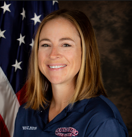 The image shows a smiling woman in a blue shirt with "SOUTHEASTRO FIRE RESCUE" on it, standing in front of an American flag.
