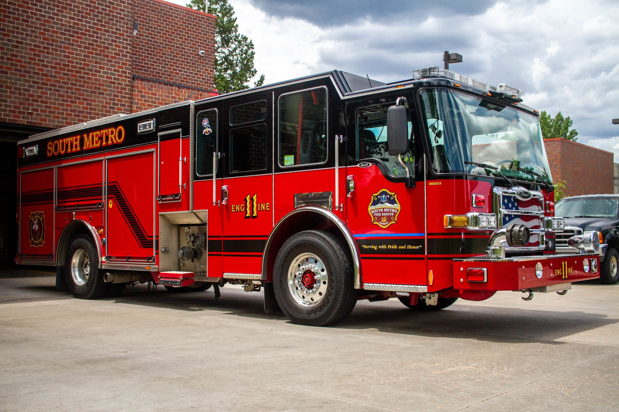 A red fire truck labeled "South Metro" parked outside a brick building under cloudy skies.