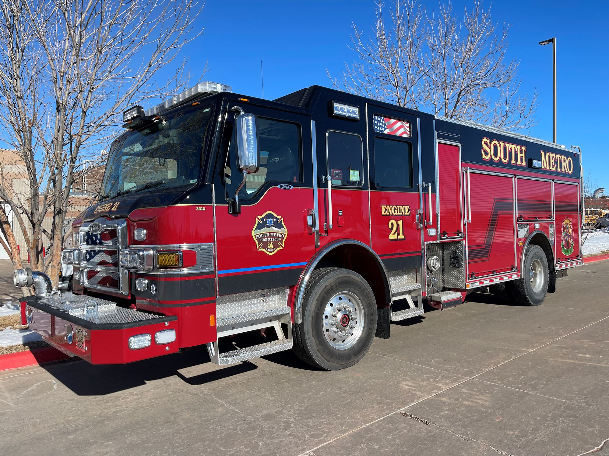 A red and black fire engine labeled "SOUTH METRO" with "Engine 21" on its side, parked on a sunny day.