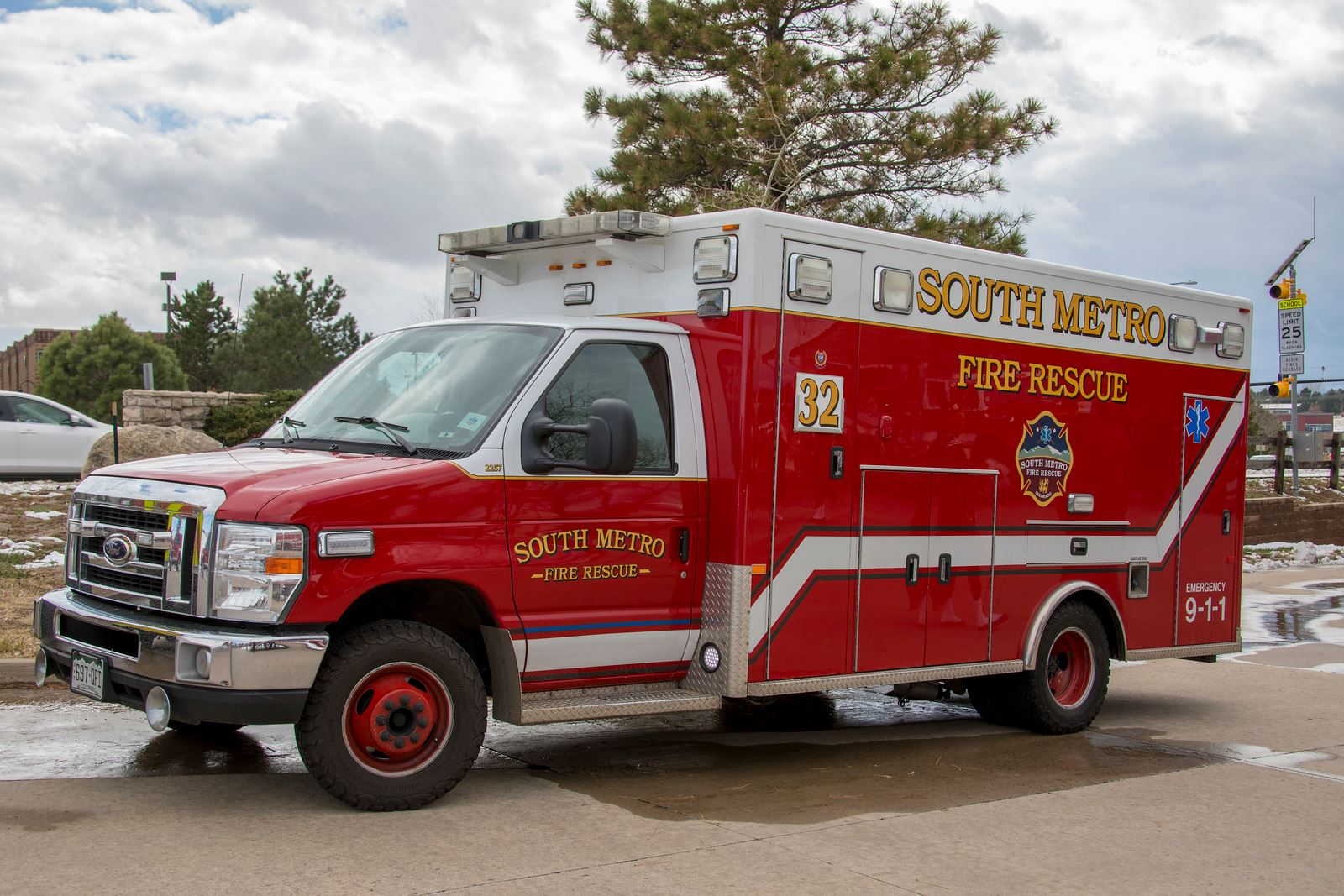 A red "South Metro Fire Rescue" ambulance is parked outdoors on a cloudy day.