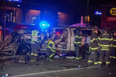 Emergency responders at night scene with a heavily damaged vehicle, blue lights flashing.