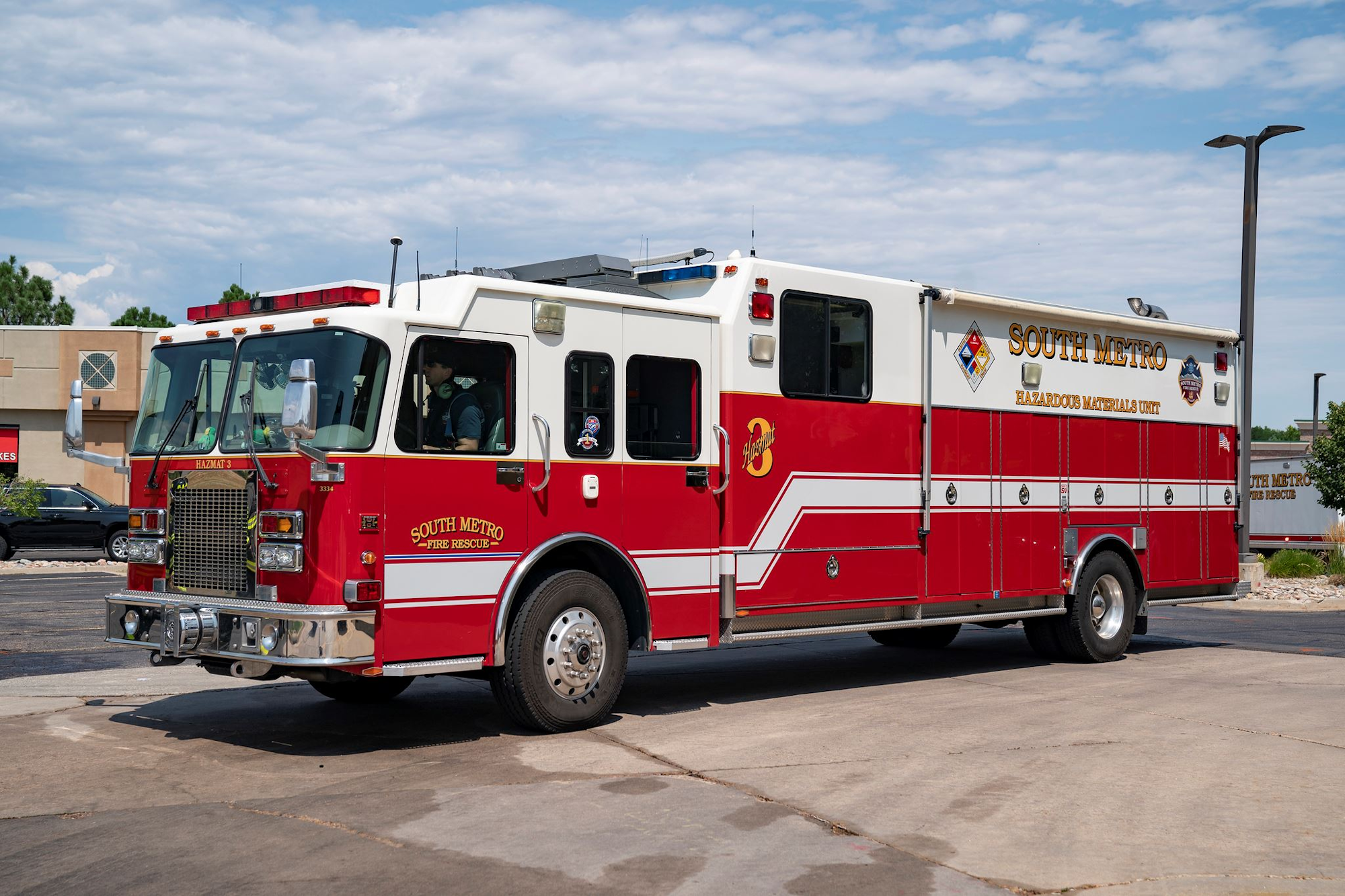 Red and white South Metro Fire Rescue Hazmat truck parked with a driver inside.
