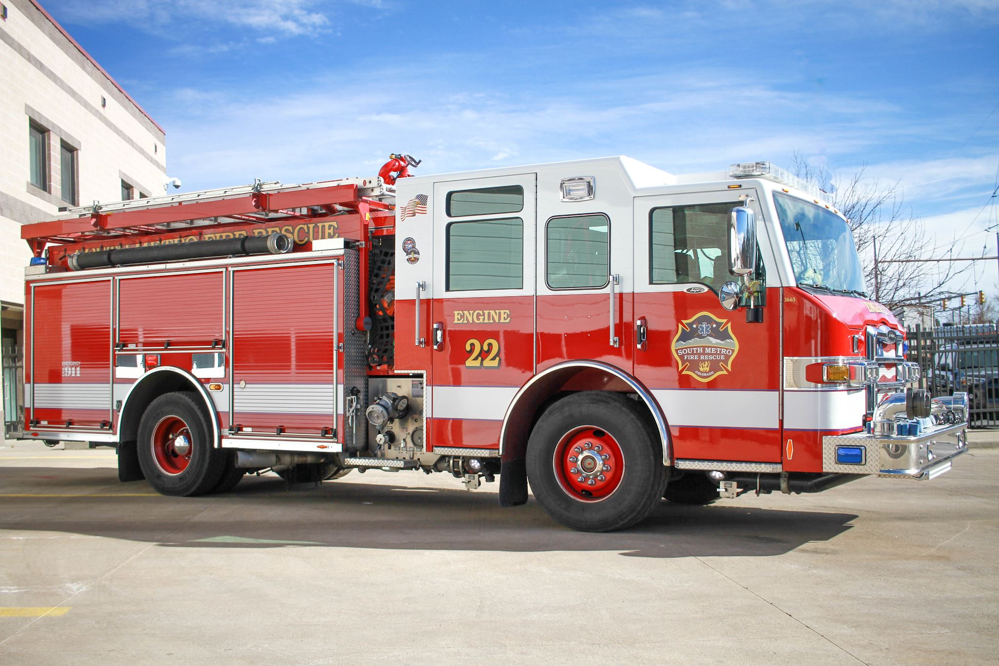 Red and white fire truck labeled "Engine 22" parked outside a building.
