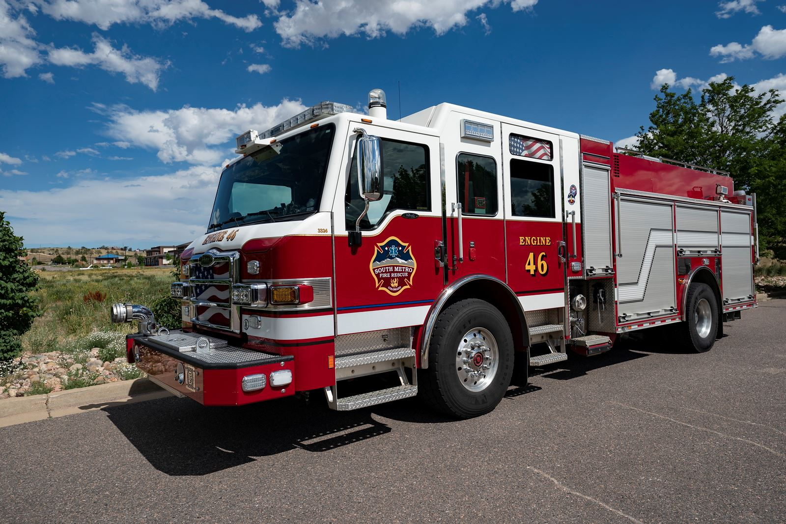 Red fire truck labeled "Engine 46" with blue sky and clouds in the background.