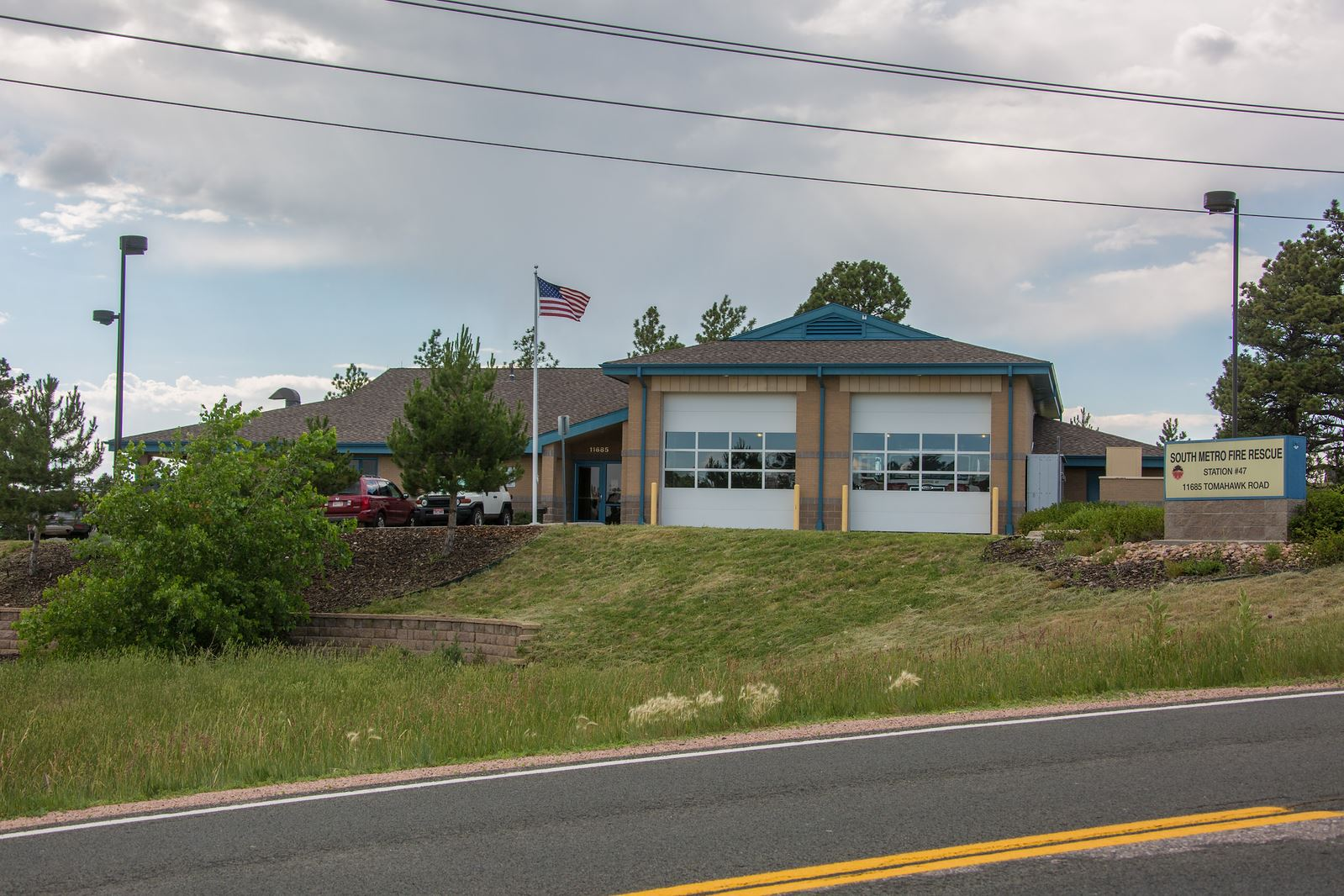 Fire station with vehicles, American flag, signage reading "South Metro Fire Rescue Station 47, 11605 Tomahawk Road."