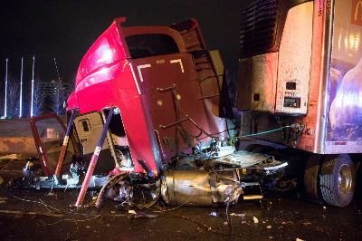 A heavily damaged red truck involved in a crash with debris scattered around.