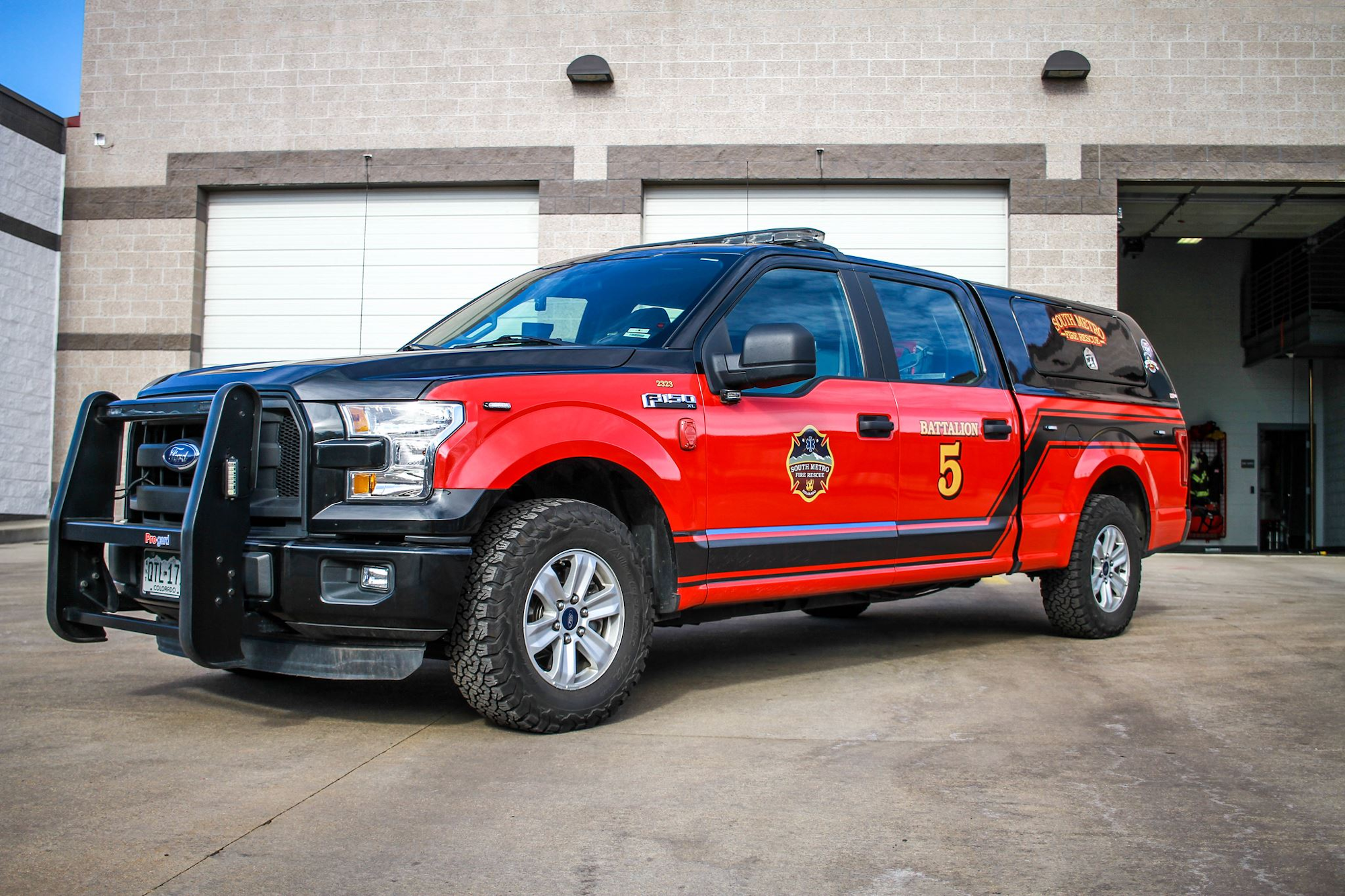A red and black fire department truck labeled "Battalion 5" parked outside a building.