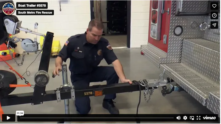 A firefighter from South Metro Fire Rescue is working on a boat trailer, performing maintenance or adjustments.