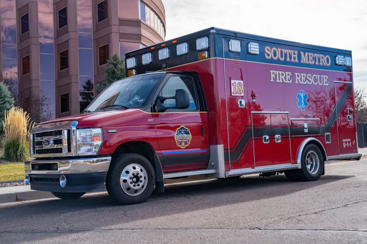 Red South Metro Fire Rescue ambulance parked on a street beside a building.
