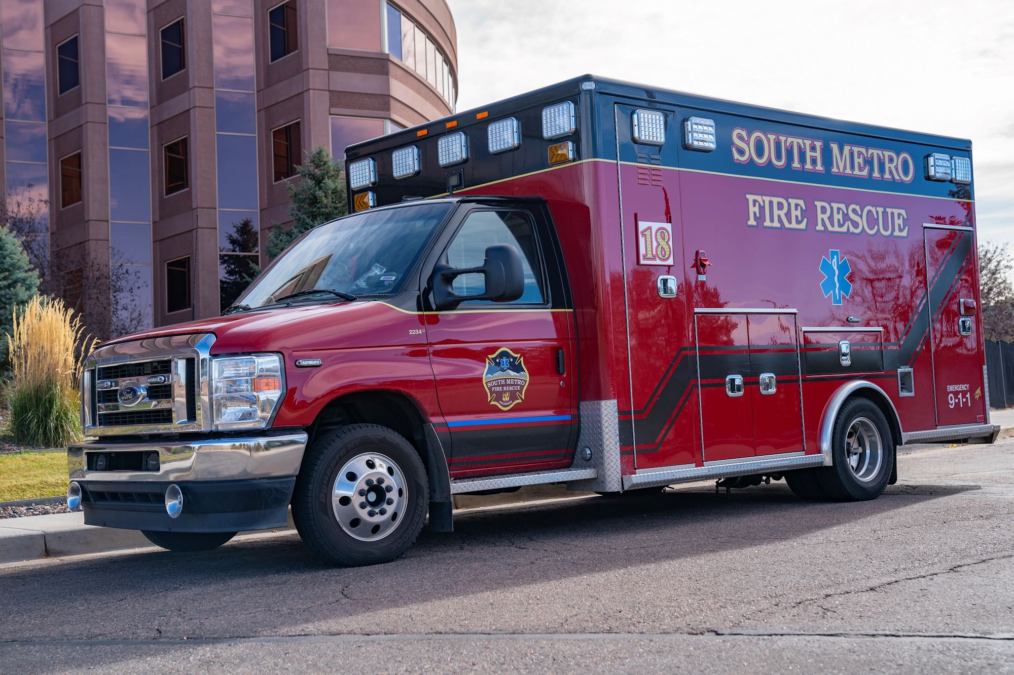 Red South Metro Fire Rescue ambulance parked on a street beside a building.