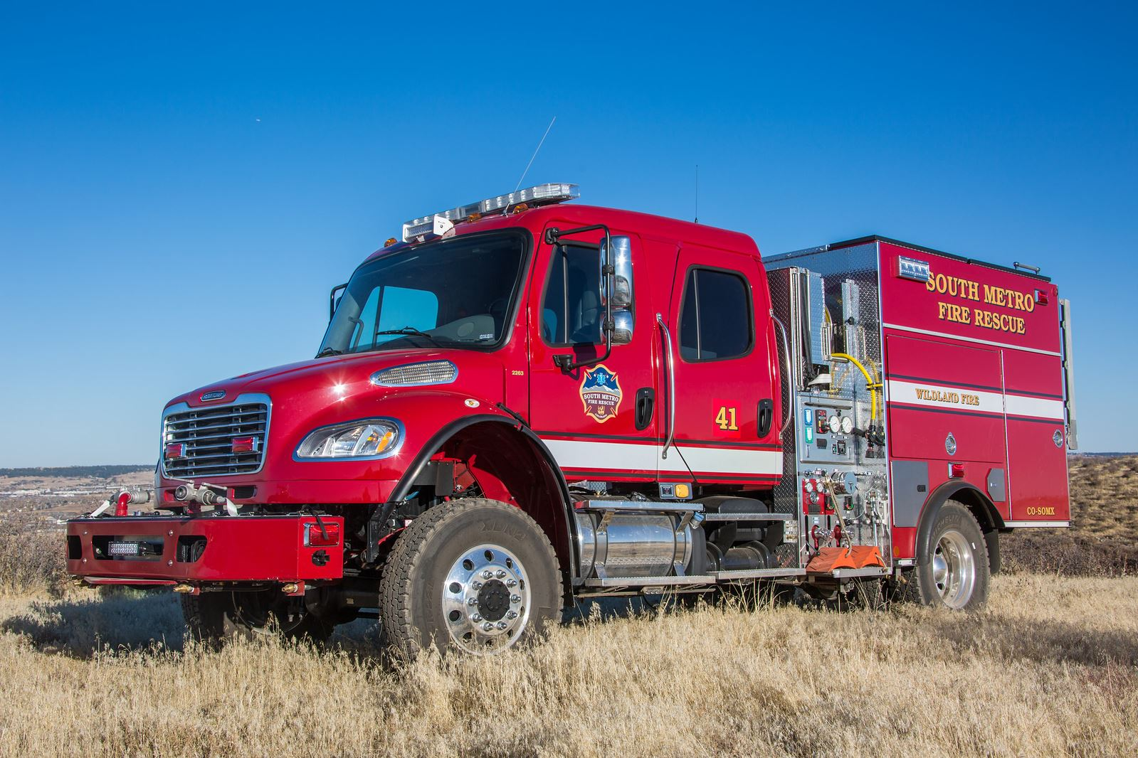 A red fire truck marked "South Metro Fire Rescue" on grass under a clear blue sky.