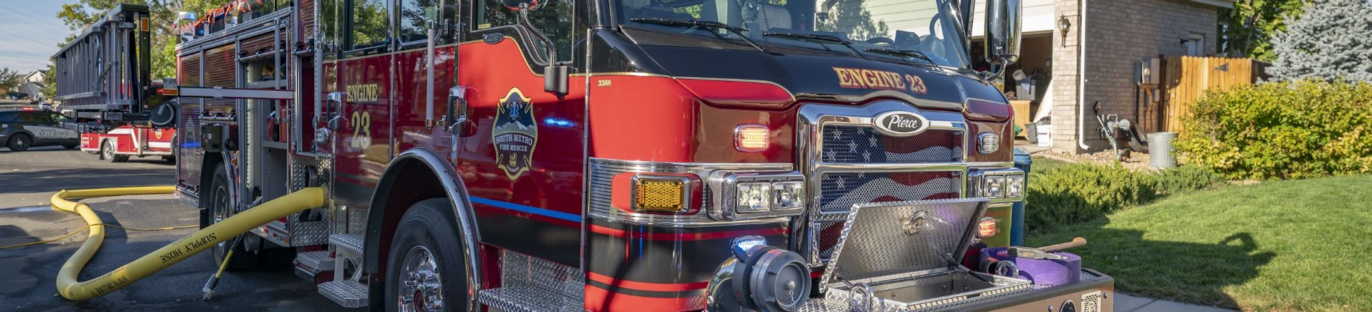 A fire engine parked on a residential street with hoses attached, ready for action.