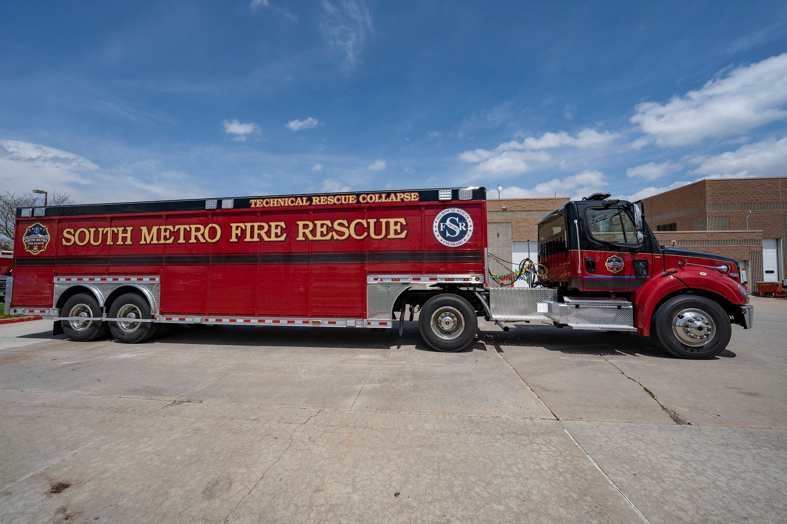 Red technical rescue vehicle labeled "South Metro Fire Rescue" parked outside a building.