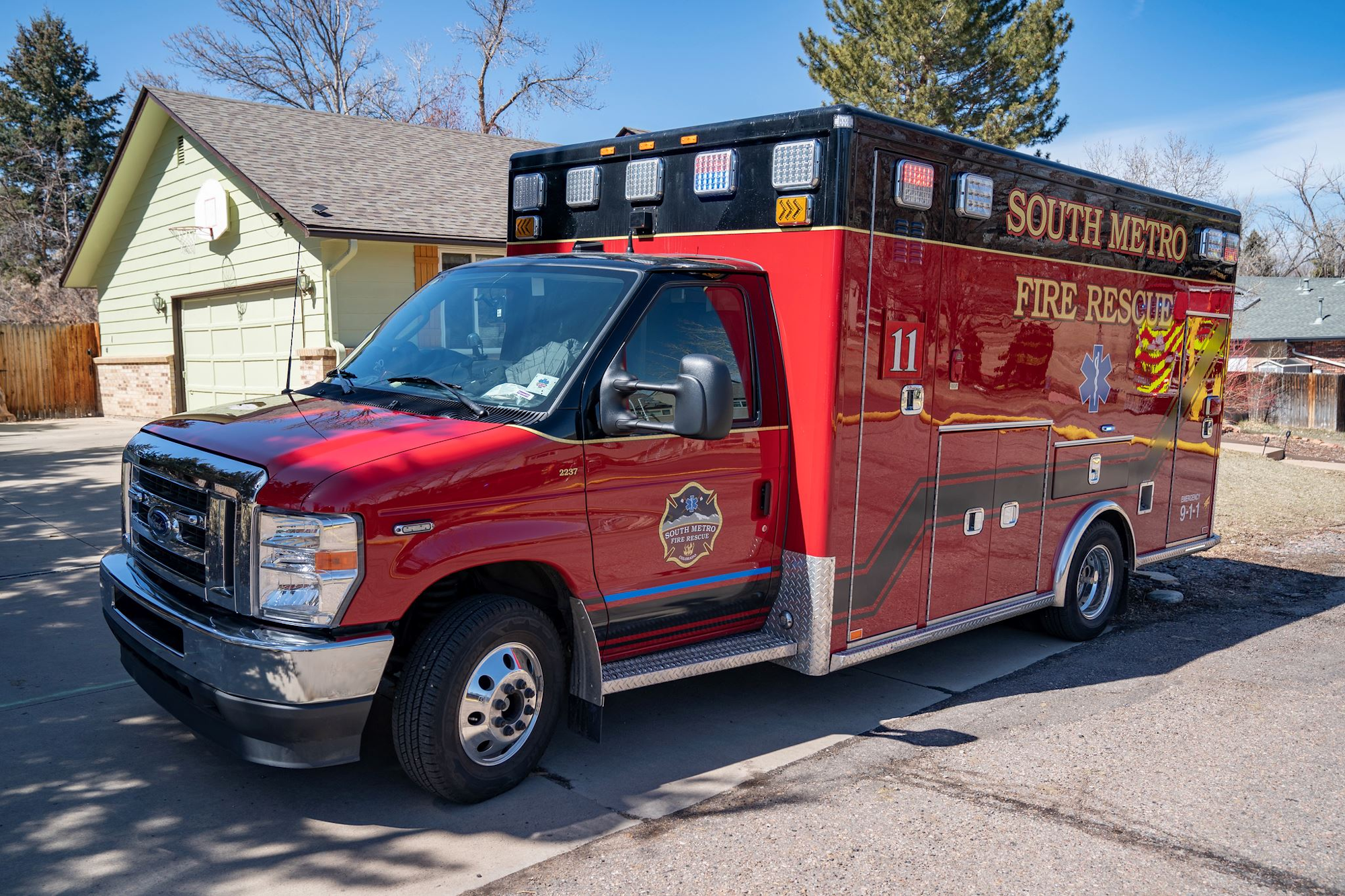A red South Metro Fire Rescue ambulance parked in a residential driveway.
