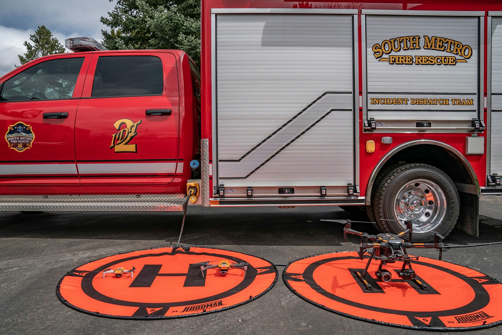 A red fire rescue truck with drones and landing pads set up for operations.