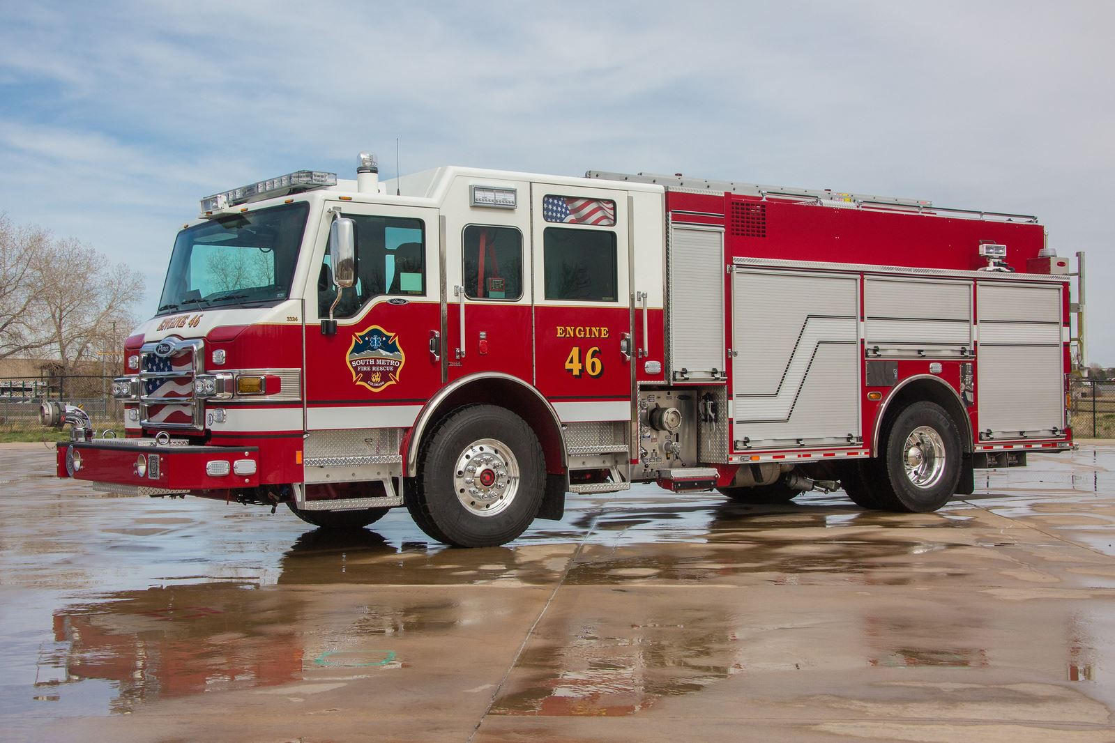 Red and white fire truck labeled "Engine 46" parked on a wet concrete surface.