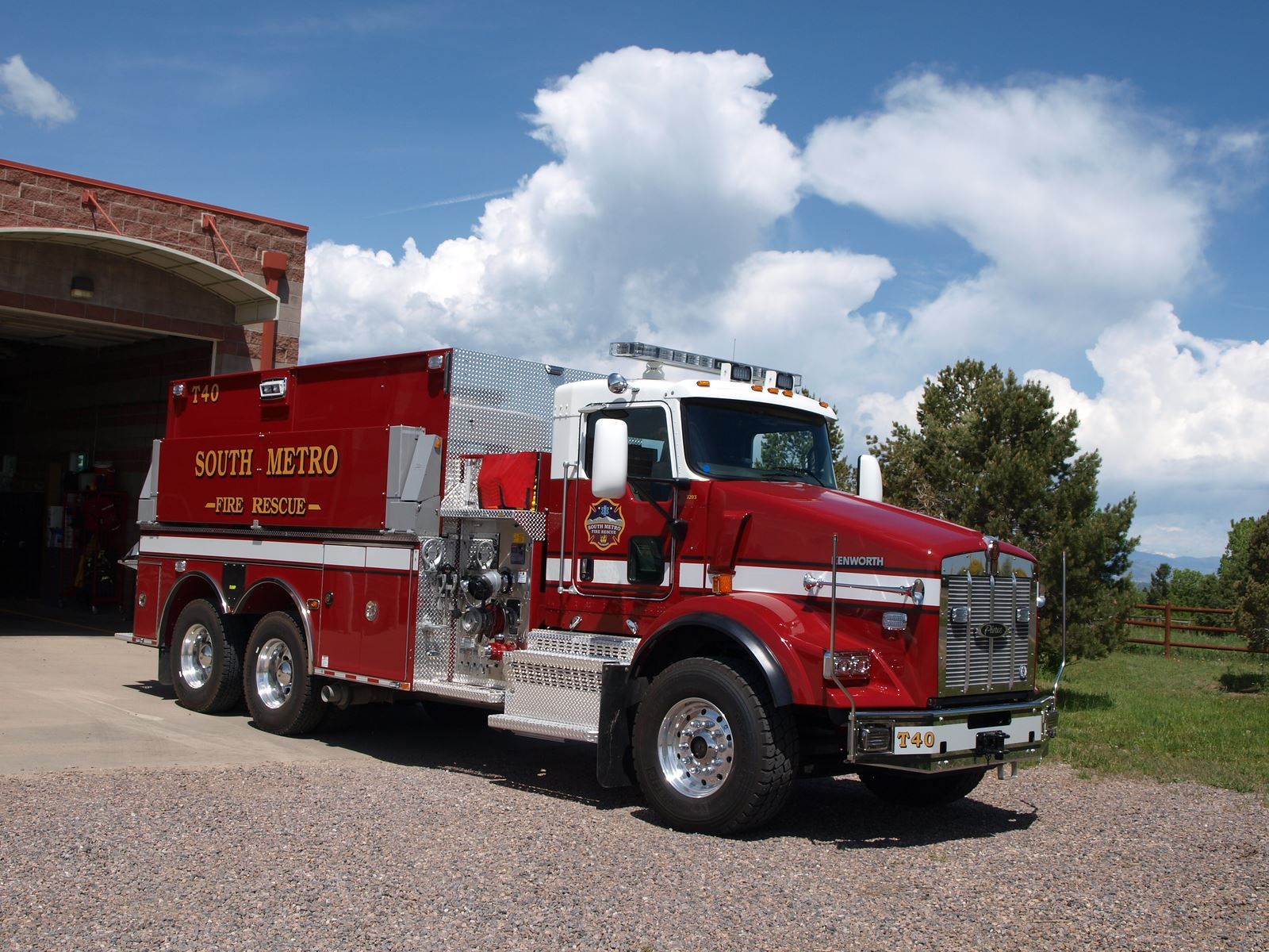 A red fire rescue truck labeled "SOUTH METRO" parked outside a building under a blue sky with clouds.