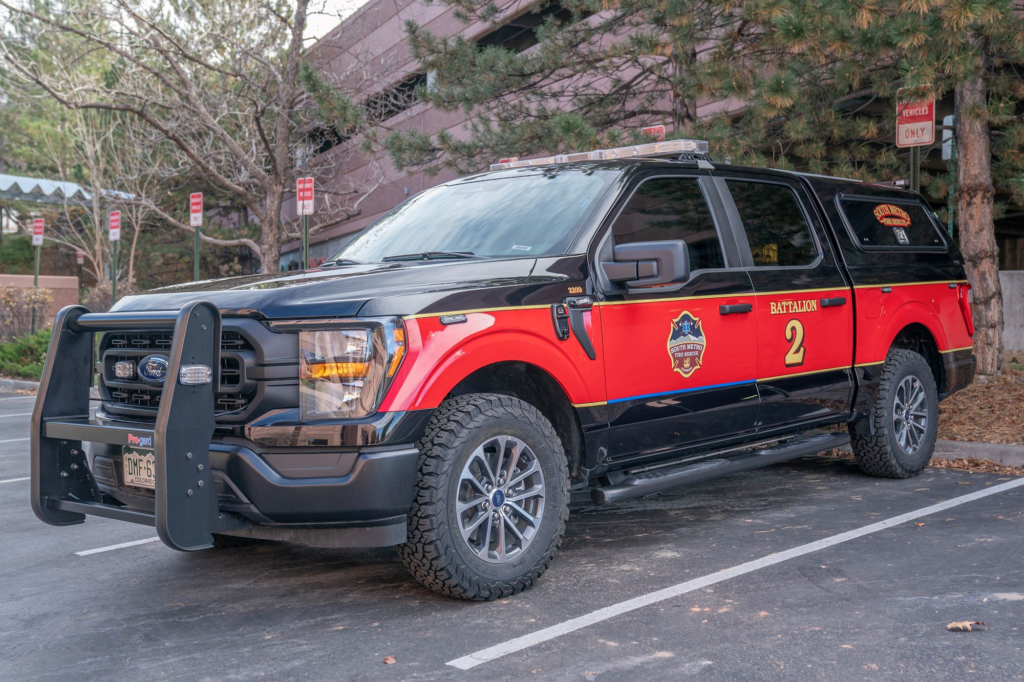Red and black fire department battalion truck labeled "2" parked outside.