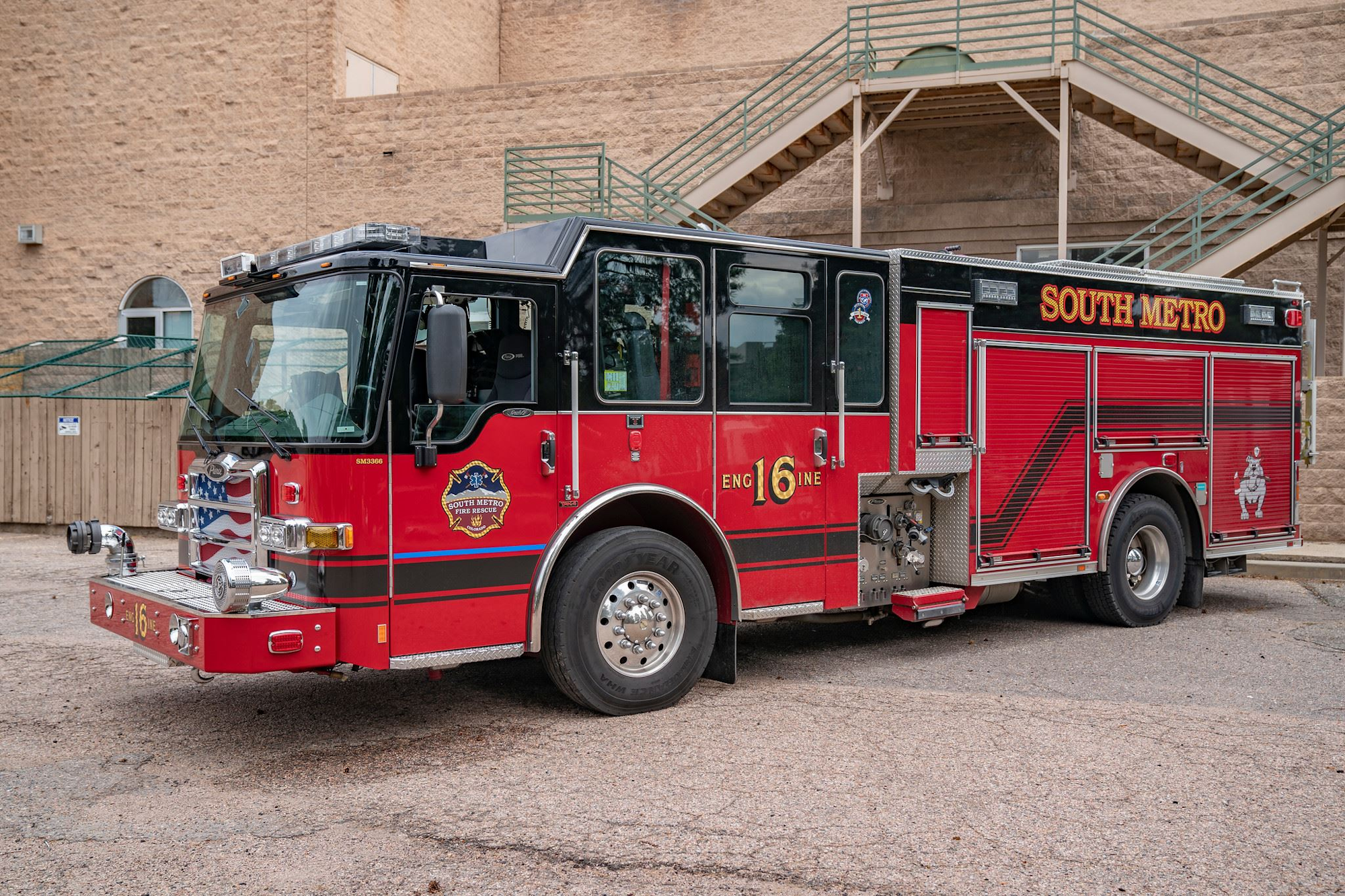 Red fire truck marked "South Metro," parked beside a building.
