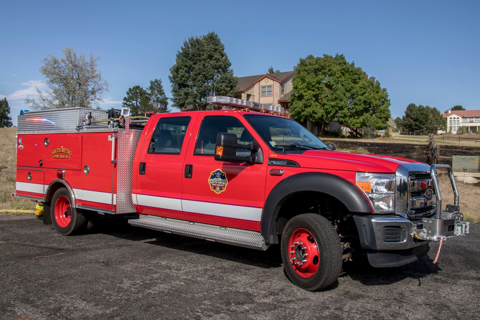A red fire rescue truck parked near trees and houses.