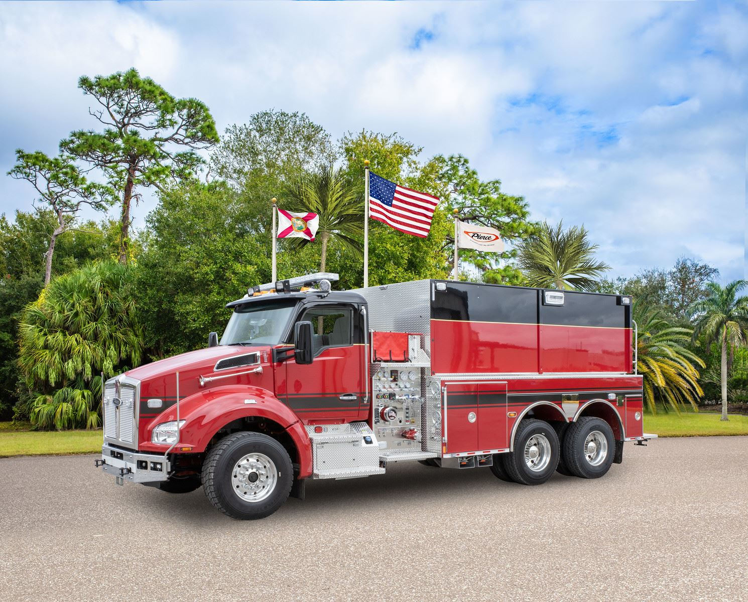 A red fire truck parked outdoors with American and state flags displayed above it.