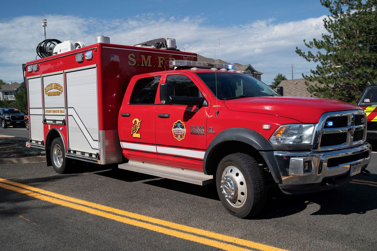 A red emergency rescue vehicle with "S.M.F.R" and "South Metro" logos is parked on the street.