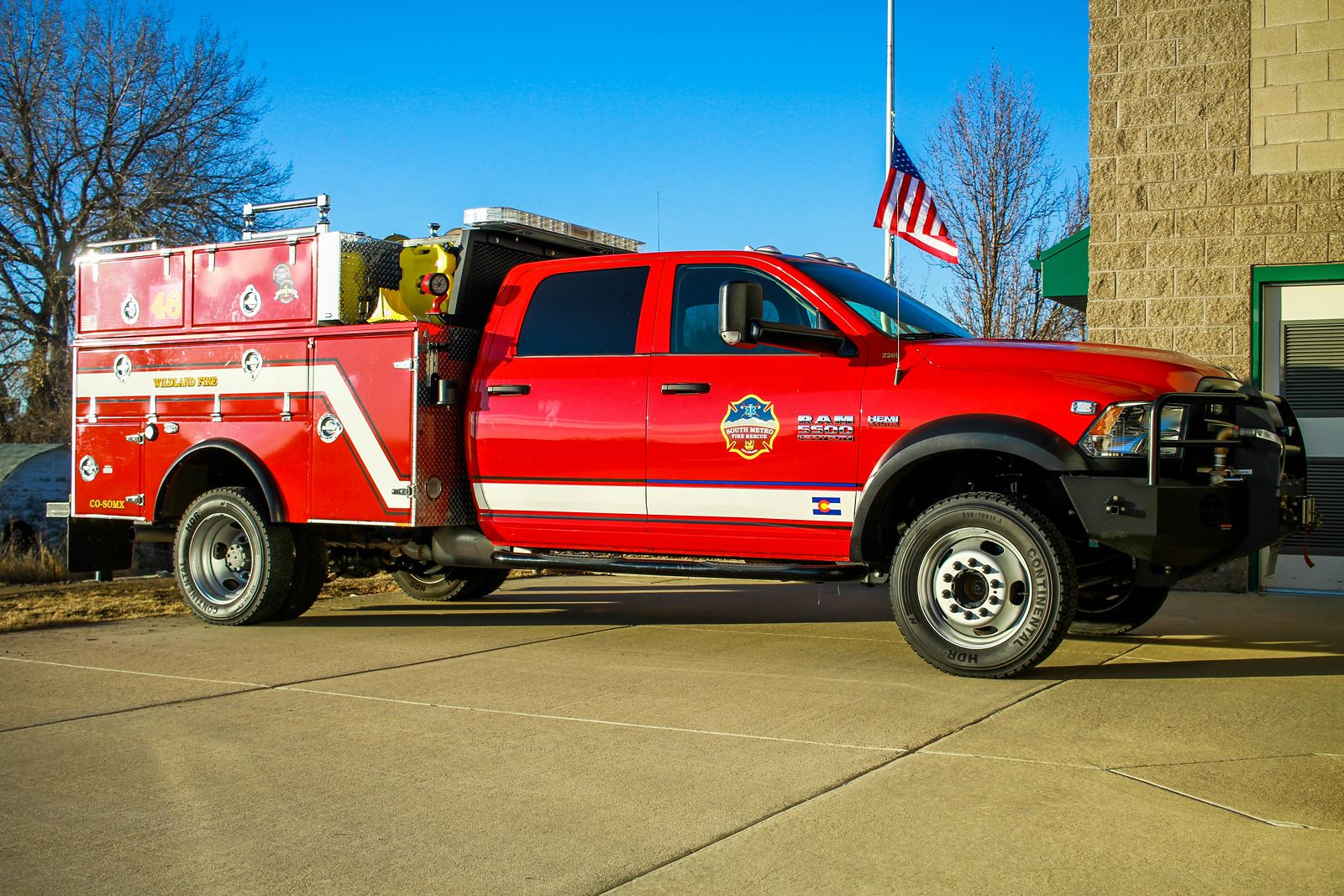 A red fire truck parked outside a building, with an American flag in the background.