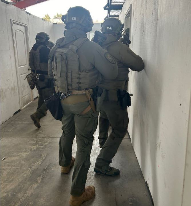 Tactical team members in gear, preparing to enter a room during a training exercise or operation.