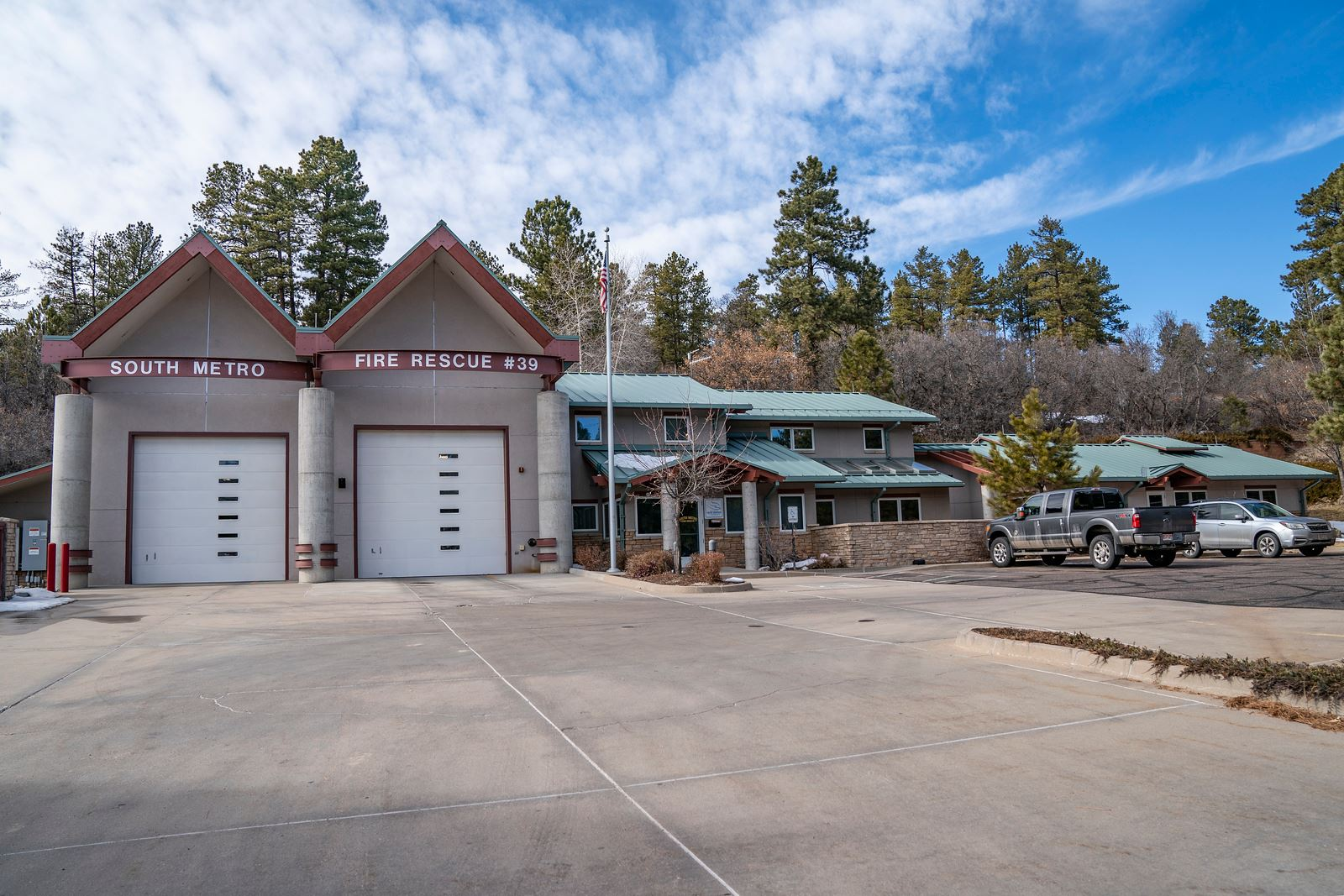 Fire station number 39 with trucks parked outside, surrounded by trees and a clear sky.