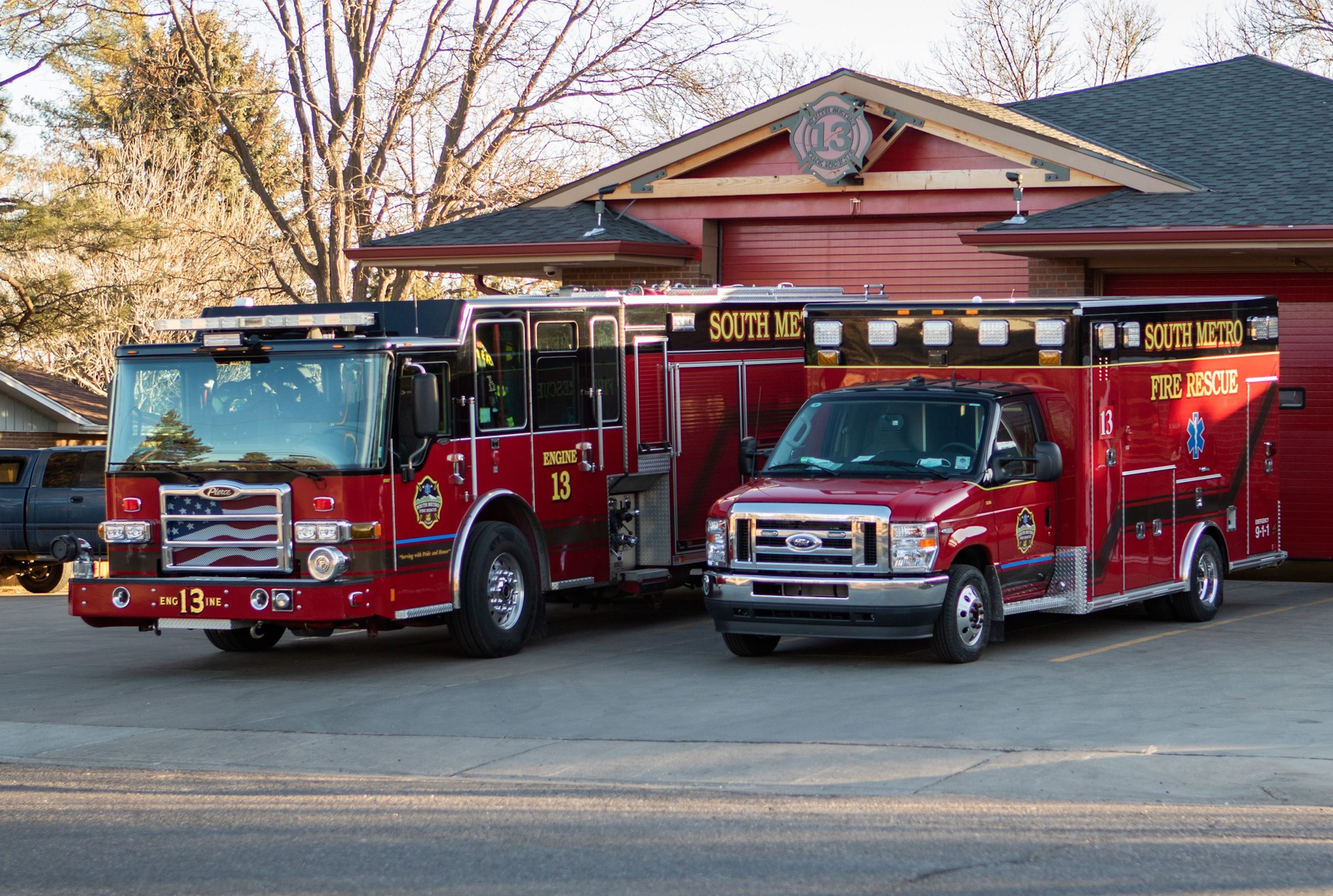 Fire truck and rescue vehicle parked outside a fire station.