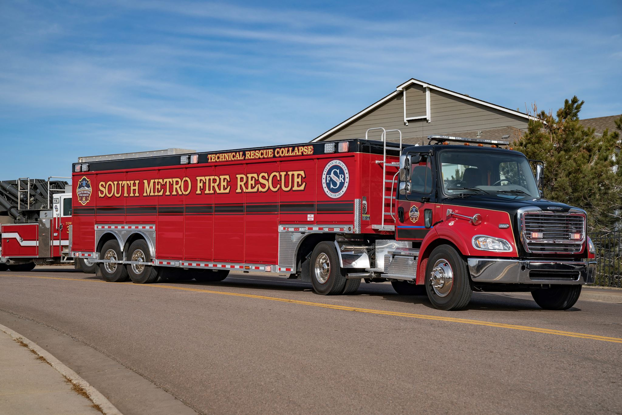 Red fire rescue truck labeled "South Metro Fire Rescue Technical Rescue Collapse" on a street.