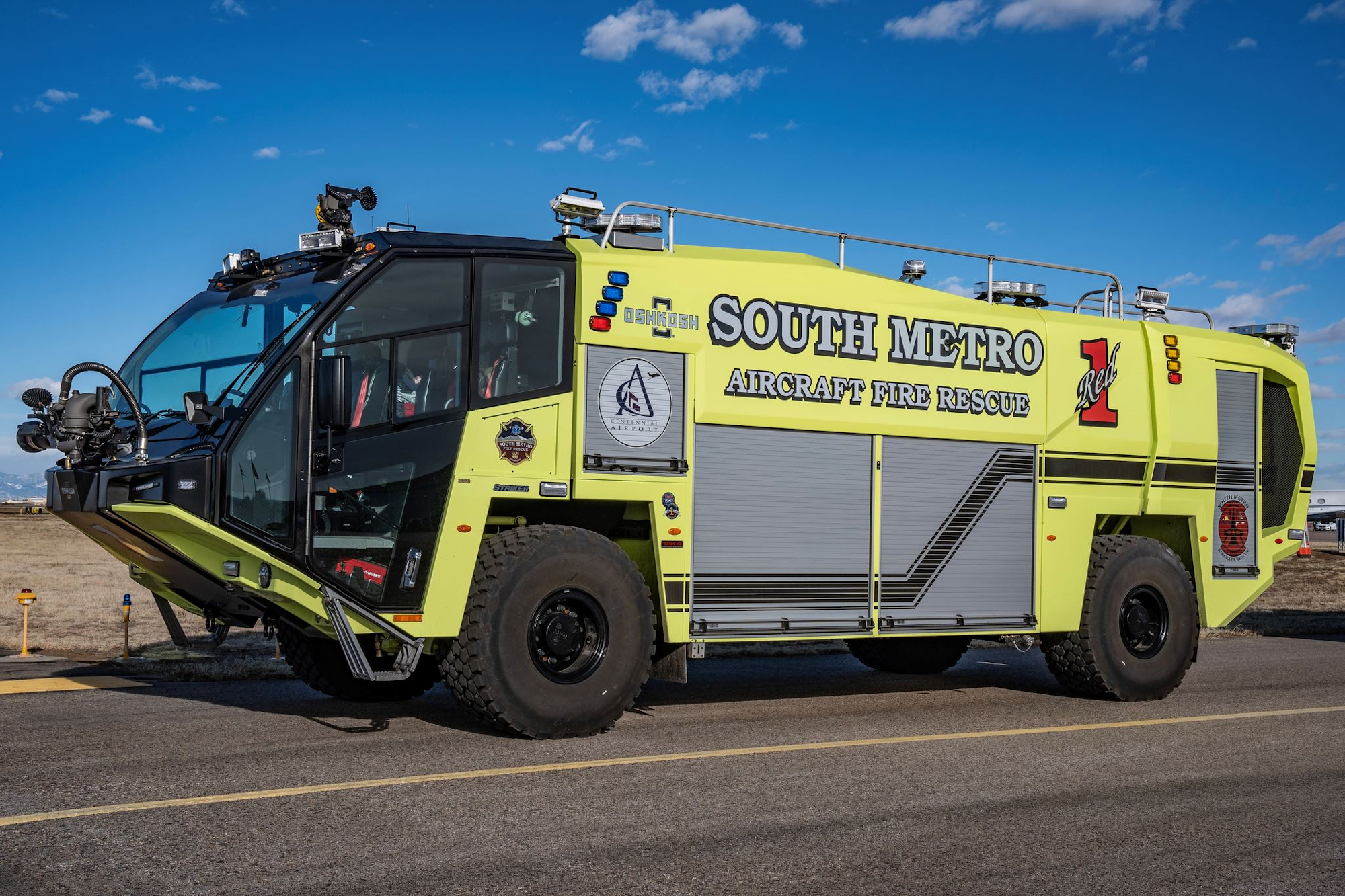 A yellow airport fire rescue vehicle labeled "SOUTH METRO" on a road with a clear blue sky.