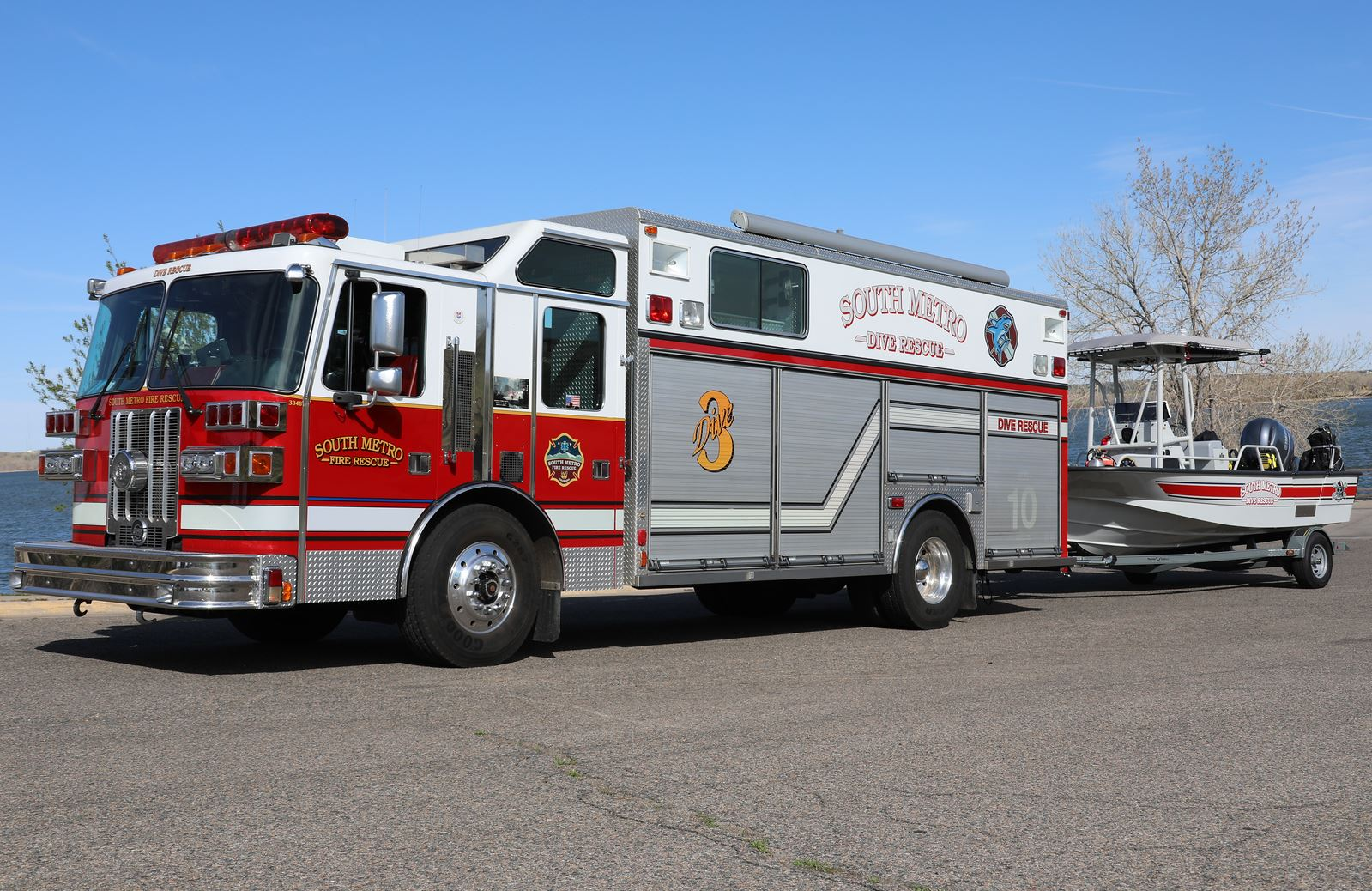 A "South Metro Fire Rescue" dive rescue truck is towing a rescue boat near a body of water.