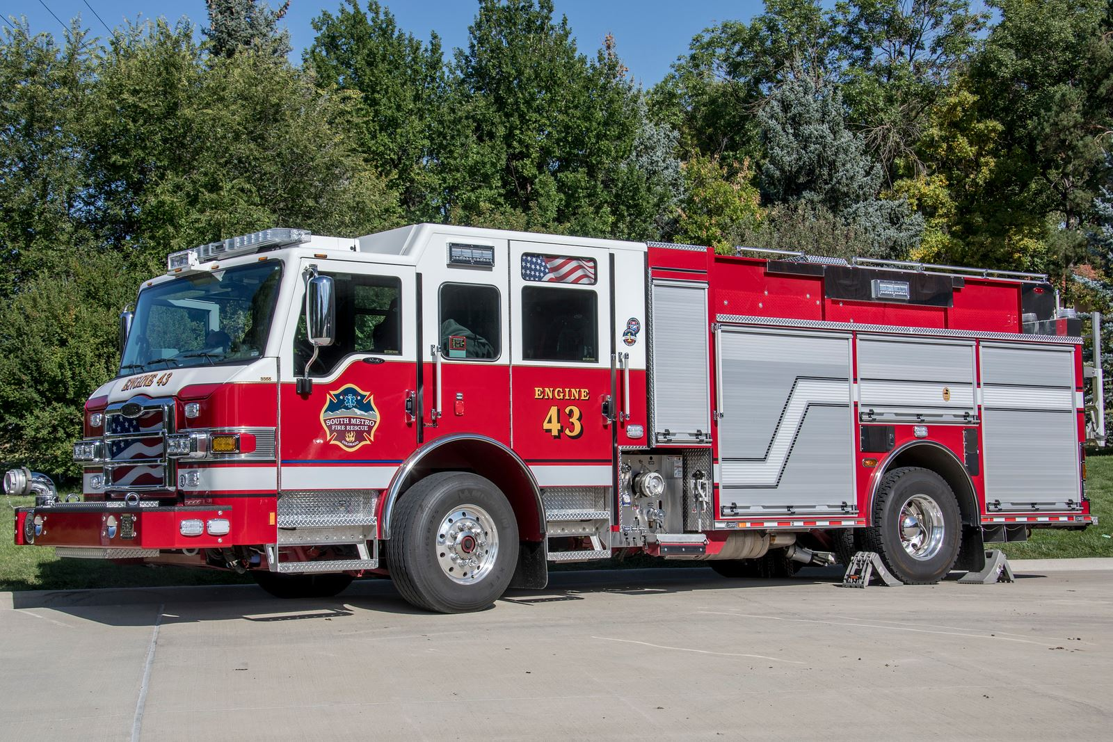 A red and white fire truck labeled "Engine 43" from the South Metro Fire Rescue, parked on a concrete surface with trees in the background.