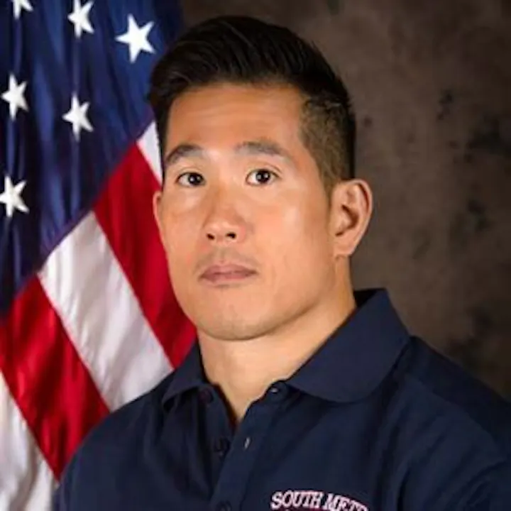 The image features a man in a blue shirt with "SOUTH" written on it, posed against a backdrop of an American flag.