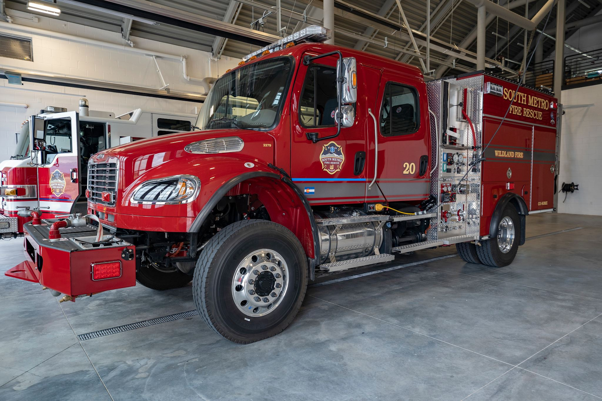 A red fire truck inside a fire station, marked "South Metro Fire Rescue" and "Wildland Fire."