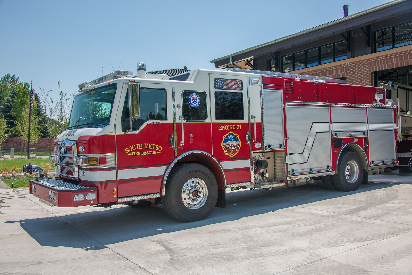 Red and white fire truck labeled "South Metro Fire Rescue Engine 31" parked outside a building.