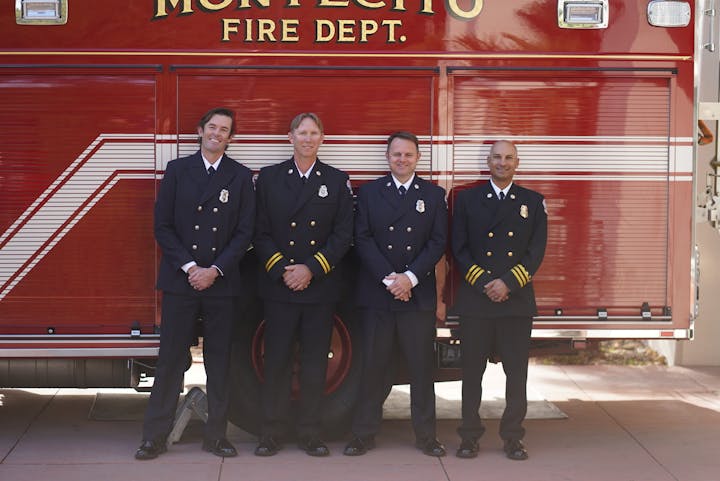Four firefighters in uniform standing in front of a Montecito Fire Department truck.