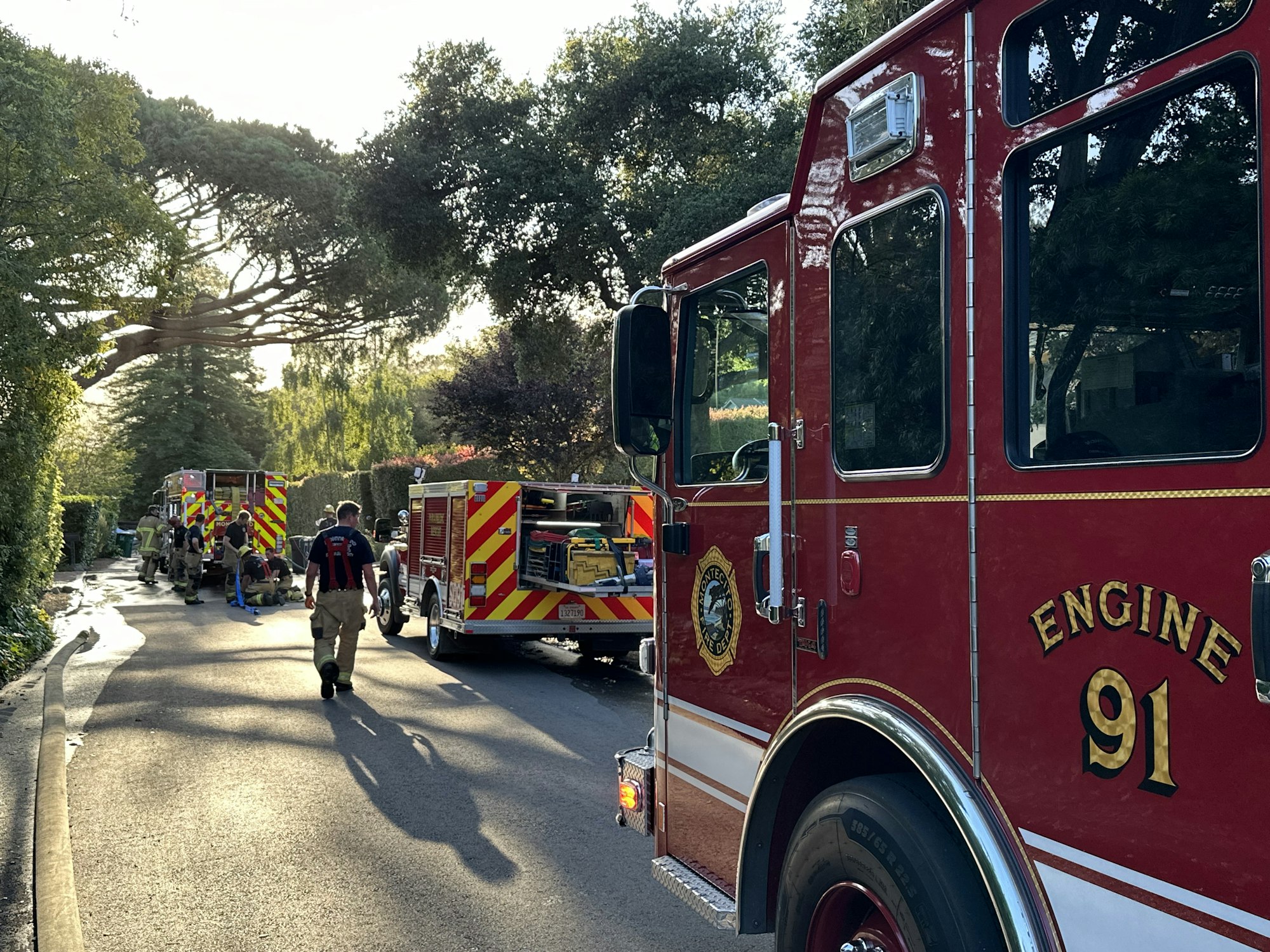 Firefighters and trucks on a road, possible emergency response scene.