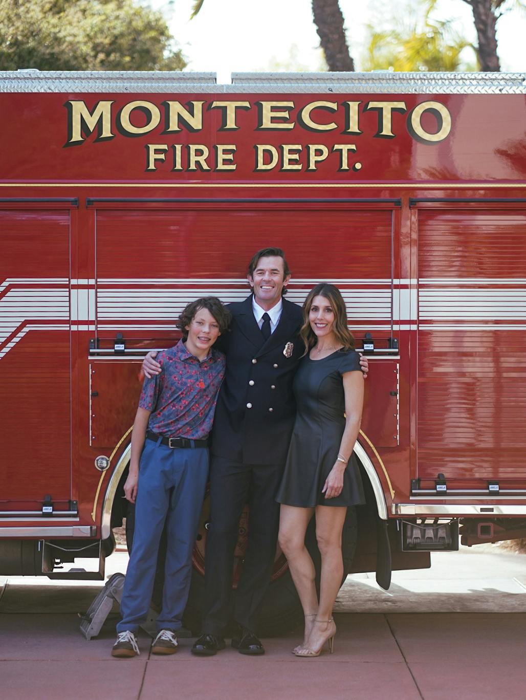 Three people standing in front of a Montecito Fire Dept. truck, one in a uniform, smiling.