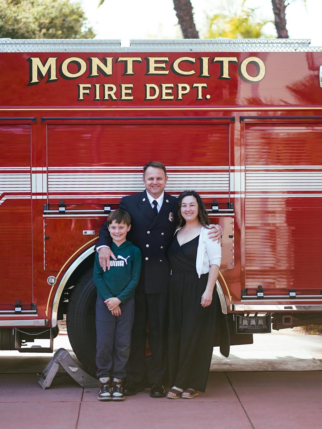 Three people standing in front of a Montecito Fire Dept. truck, smiling.