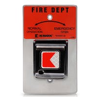 The image shows a red and silver fire department key switch, with indications for normal and emergency operation.