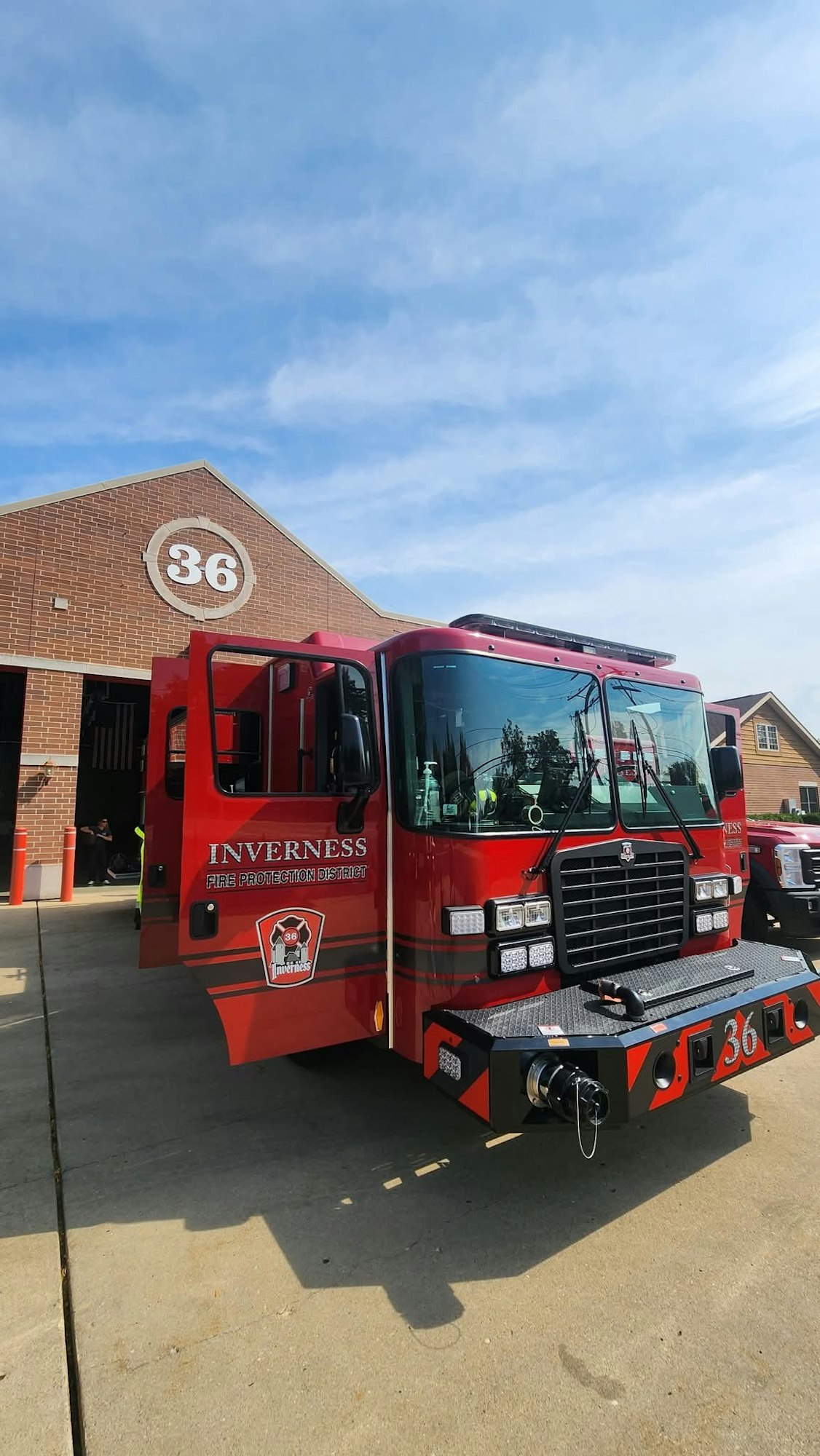 A red fire truck in front of a fire station with the number 36.