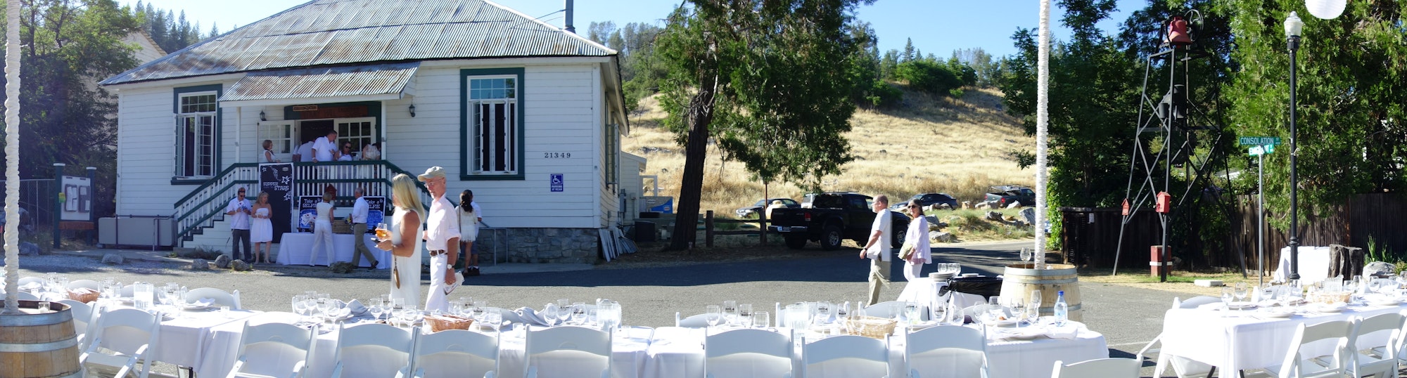 Dining on Main St. Volcano setup with tables, people mingling, a historic building, and a clear sky.