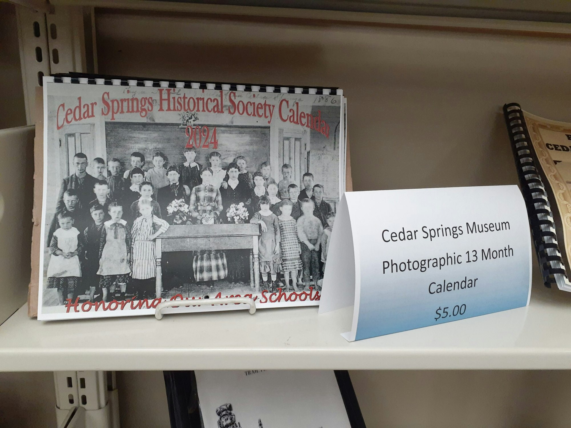 Cedar Springs Historical Society 2024 calendar on a shelf, priced at $5.00.